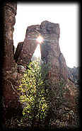 Pillars of volcanic rock frame the setting sun along a trail in the Superstition Mountains, Arizona.